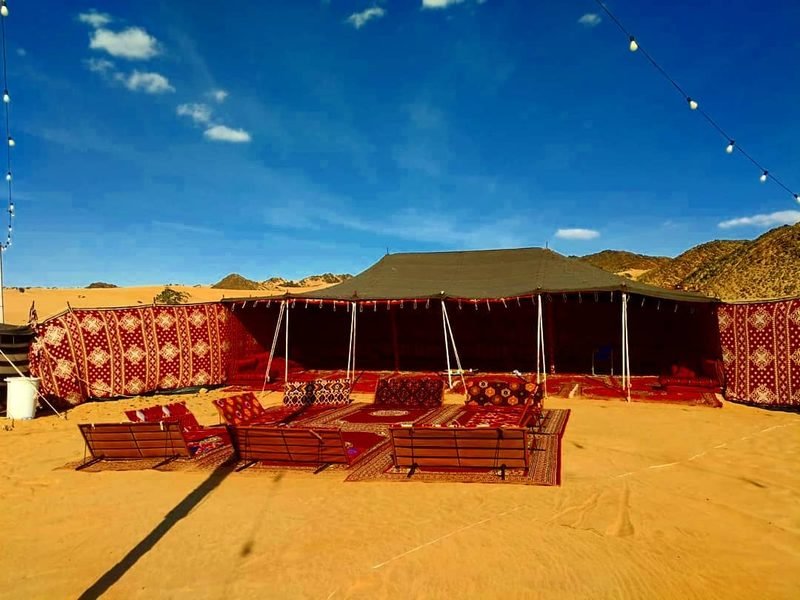 Bedouin tent with red carpets under a blue sky
